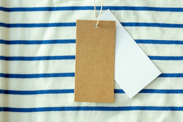 Canvas Print - Blank brown and white cardboard price tag or label with thread on striped t-shirt. Top view