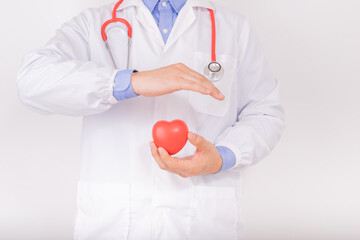 Doctor wear white lab coat with red stethoscope and holding red heart in hands and protect it by another hand. Cardiology healthcare, healthy heart protection, cardiac diseases concept