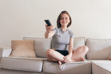 Cheerful Woman With Remote Controller On Sofa