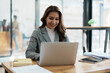 © Jirapong - Portrait of a woman business owner showing a happy smiling face as he has successfully invested her business using computers and financial budget documents at work