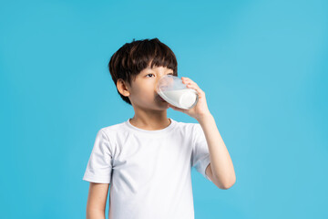 Portrait of asian boy holding cup of milk, isolated on blue background