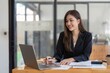 © Natee Meepian - Asian Business woman using calculator and laptop for doing math finance on an office desk, tax, report, accounting, statistics, and analytical research concept