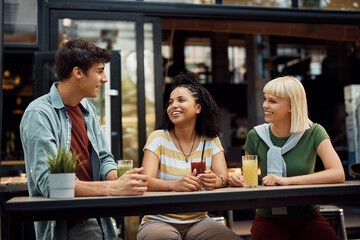 Wall Mural - Multiracial group of happy friends enjoys in conversation while drinking juice in cafe.