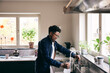 © Maskot - Side view of mature man filling pitcher from faucet in kitchen at home