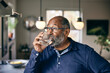 © Maskot - Contemplative senior man drinking water at home