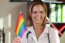 Smiling Female Doctor Holding Rainbow Flag On Hand