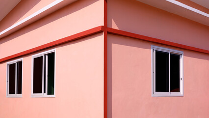 Wall Mural - Exterior Architecture background of glass sliding windows on orange concrete wall of modern house with light and shadow on surface in Minimal style and symmetry view