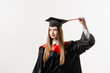 © Rabizo Anatolii - Graduate girl with master degree in black graduation gown and cap on white background. Happy young woman successfully graduated from the university with honors.