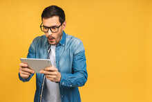 Amazed Shocked Happy Bearded Man Using Digital Tablet Looking Shocked About Social Media News, Astonished Man Shopper Consumer Surprised Excited By Online Win Isolated Over Yellow Background.