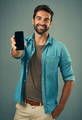 Poster - Take a look and tell me what you think. Studio portrait of a handsome young man holding a cellphone with a blank screen against a grey background.