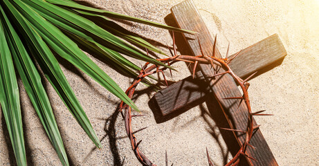 crown of thorns with wooden cross and palm leaf on sand. good friday concept