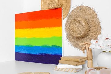 Poster - Painting of LGBT flag, wooden hand and books on table near light wall