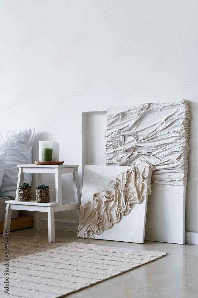 Beautiful creative artwork and stepladder near light wall in bedroom