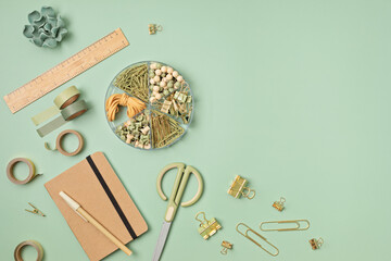 flatlay of office supplies made of recycled materials on green background with copy space for text. 