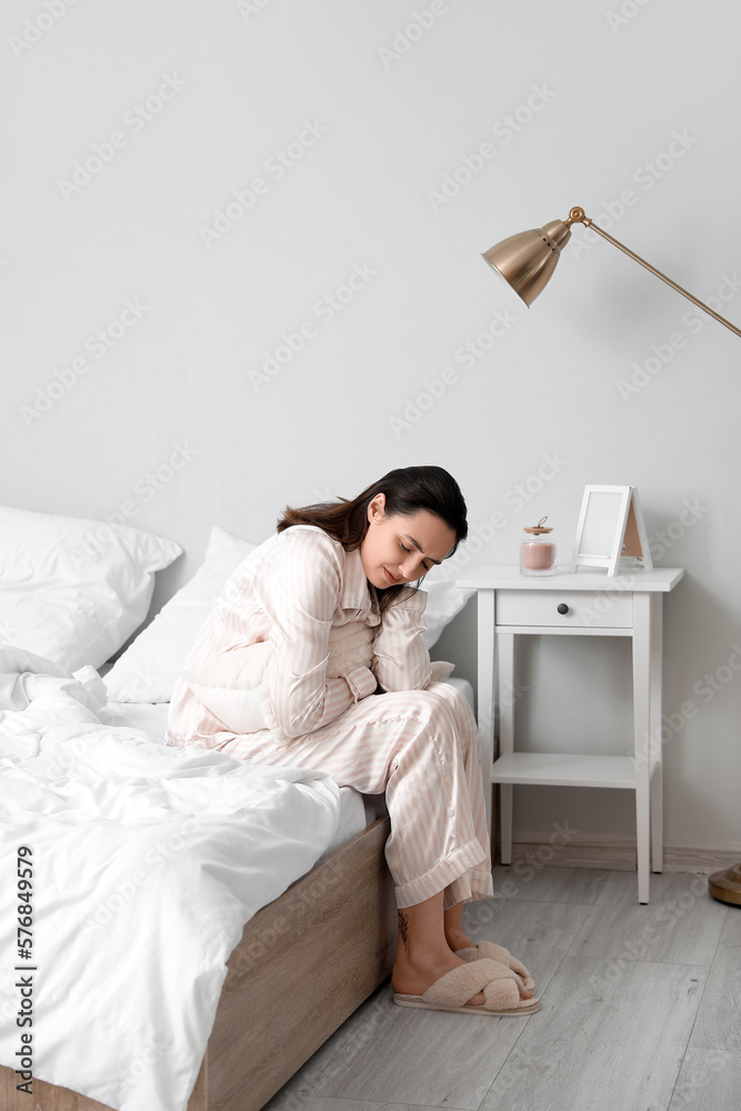 Young woman having menstrual cramps in bedroom