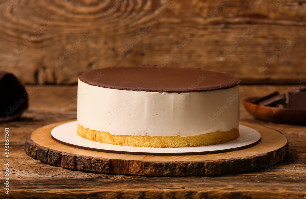 Board with tasty birds milk cake on wooden table