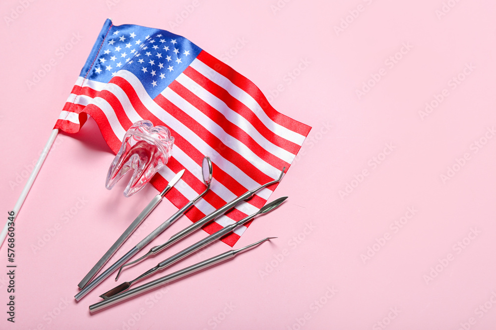 Dental tools with plastic tooth and USA flag on pink background