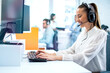 Dedicated smiling woman in headset using computer in office. Call center, customer service support concept.