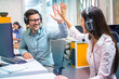 © Bojan - Customer support representative operators giving high five to each other celebrating successful task done at office.