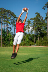 Wall Mural - Youth male football player leaping up to make a spectacular catch 