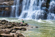 A man in a whitewater kayak, kayaking the Caney Fork River under The Twin Falls at Rock Island State Park in Tennessee.