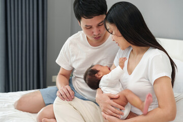 Wall Mural - parent (mother and father) trying to consoling crying baby on bed