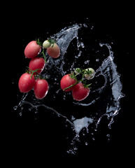 Wall Mural - fresh red tomato with water splash and air bubbles isolated on black background.