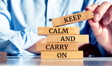 Close Up On Businessman Holding A Wooden Block With "Keep Calm And Carry On" Message
