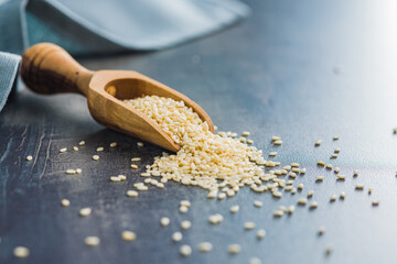 Poster - Dried sesame seeds in wooden scoop.