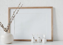 Easter Background. Wooden Frame Mockup With Copy Space,spring Willow Branches In A Vase And Easter Eggs And Funny Bunny Decor Near White Textured Wall In Neutral Colors.