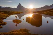 With The Matterhorn In The Background, A Female Hiker Is Standing On A Little Island In A Mountain Lake, Watching The Sun Go Down Behind The Mountain Peaks Of Wallis.