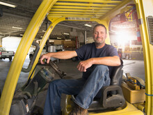 A Well-built Man Sits On The Driverâ€™s Sit Of A Utility Vehicle.