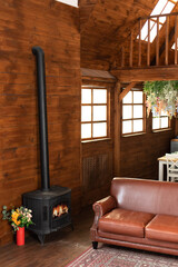 Wall Mural - Interior cozy living room with comfortable brown leather sofa and carpet on floor. Black modern Cast iron wood stove at home. Traditional heating system. Classic fire place with wood burning inside	