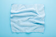 Wrinkled dry soft microfiber rag for different surfaces wiping. Closeup. Light blue table background. Pastel color. Top down view.