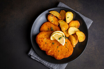 Wall Mural - Chicken schnitzel with sauce, fried potatoes and lemon in a plate