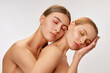 © Lustre Art Group  - Portrait of two adorable young girls with well-kept skin posing with closed eyes over light background. Models with bare shoulders. Concept of beauty, emotions, skin care and health
