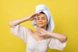 © Budjak Studio - A pretty young girl with a scrub mask on her face poses for the camera and smiles against a yellow background.