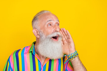 Portrait of cheerful optimistic old man with long beard wear colorful shirt scream look empty space isolated on yellow color background