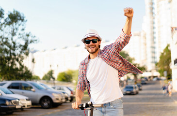 Wall Mural - Young handsome man riding an electric scooter on vacation, having fun. Ecological transportation concept.