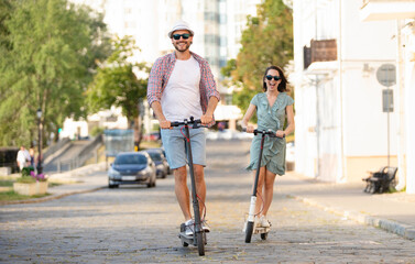 Happy young couple in love on vacation having fun, driving electric scooter through the city. Eco transport