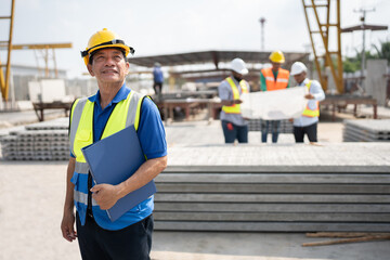 Wall Mural - Portrait Asia senior engineer man holding document file with team working with paper work and precast cement factory background	