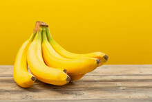 bunch of bananas on  wooden table on yellow background