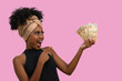 © Edson Souza - woman with money, young smiling woman points to Brazilian money, on pink background
