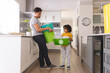© Wavebreak Media - Hispanic man teaching son about waste management while standing in kitchen at home