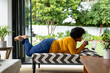 © Wavebreak Media - Full length side view of african american mid adult woman using laptop while lying on couch at home