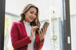 © ArLawKa - Asian female worker sitting in remote office holding smartphone using business applications or mobile work tools. Female freelancer checking email on mobile phone