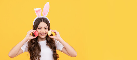 Canvas Print - positive child in bunny ears hold eggs on yellow background. Easter child horizontal poster. Web banner header of bunny kid, copy space.