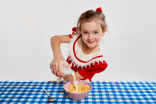 Cute Beautiful Little Girl Having Yummy Healthy Breakfast With Cereal, Posing Against Grey Studio Background. Concept Of Childhood, Game, Friendship, Activity, Leisure Time, Retro Style, Fashion.