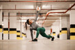 © dusanpetkovic1 - A flexible sportswoman is stretching her legs and backs in underground parking lot.