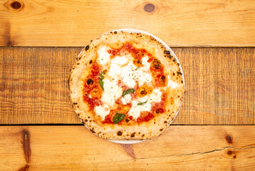 Wall Mural - The most typical, simple and famous Italian stone-baked margherita pizza on a wooden table